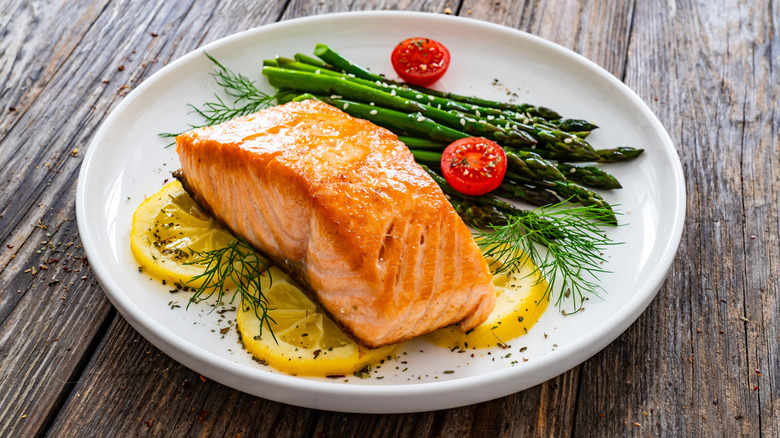 A plate of salmon and asparagus on a wooden surface