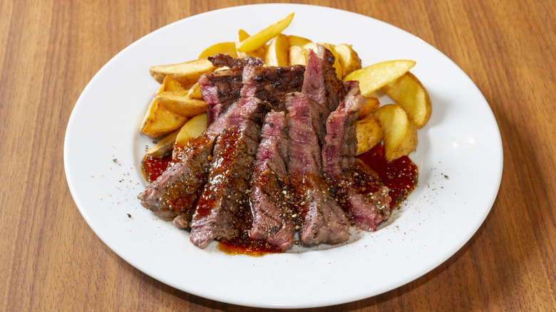 A grilled beef steak and fries on a plate