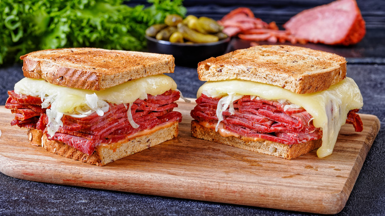 a Reuben sandwich cut in half sitting on a cutting board