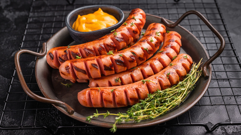 grilled hot dogs in a cast iron pan sitting beside garnishes