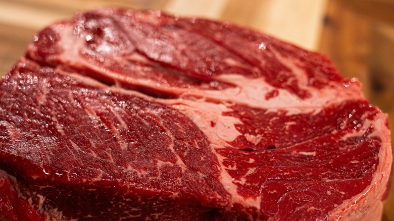 A raw chuck roast on a wooden board