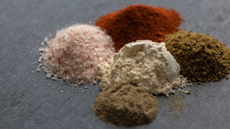 Multiple scoops of seasonings, including paprika and salt