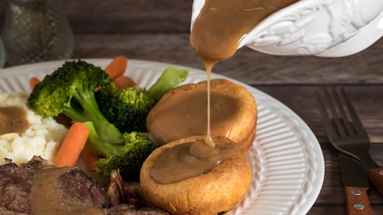 Gravy being poured from a boat onto a roast dinner