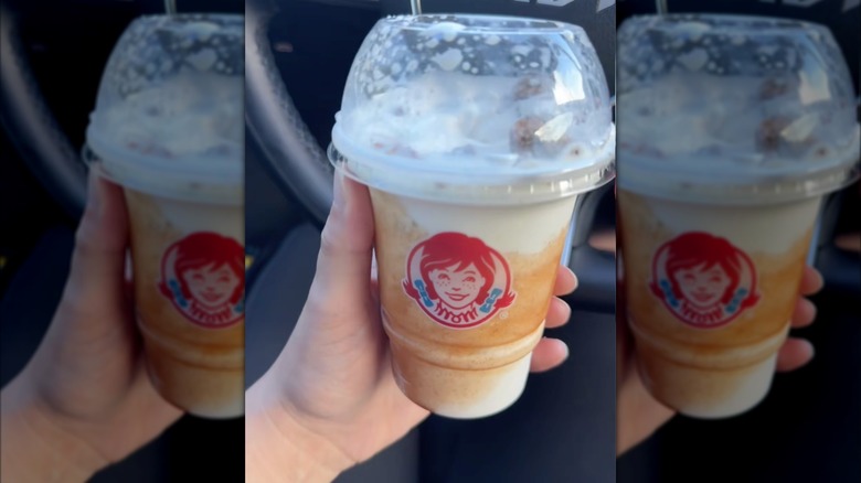 Close-up of a hand holding a cup of Wendy's Apple Crumble Frosty