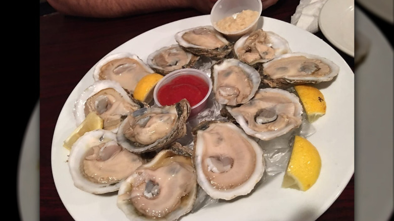 Plate of oysters with lemon wedges and sauce