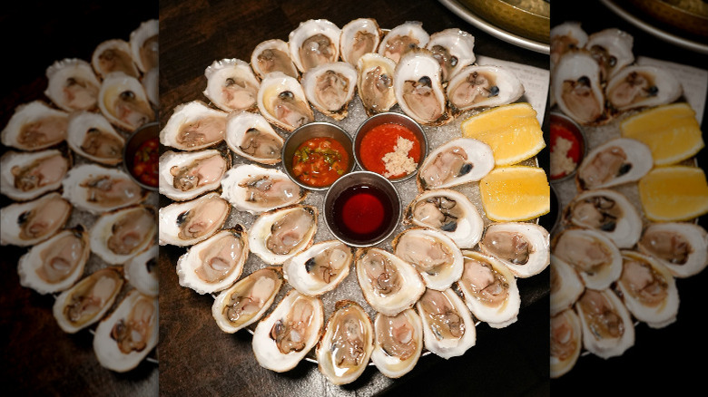 Platter of oysters on ice with lemon wedges