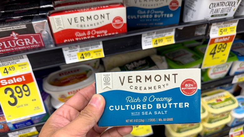 A person holding a pack of Vermont Creamery butter in a grocery store