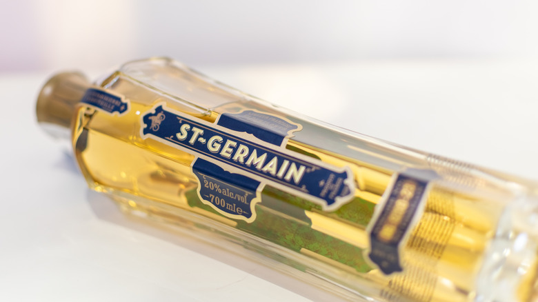 A close up of a bottle of St Germain Elderflower liqueur lying on its side on a white background