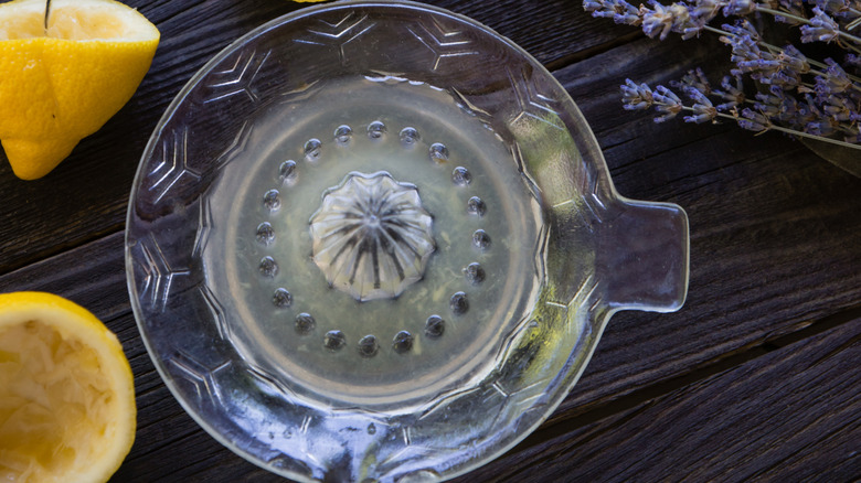 A glass lemon juicer with lemon halves next to it