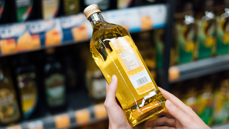 A woman holding a bottle of olive oil at the supermarket