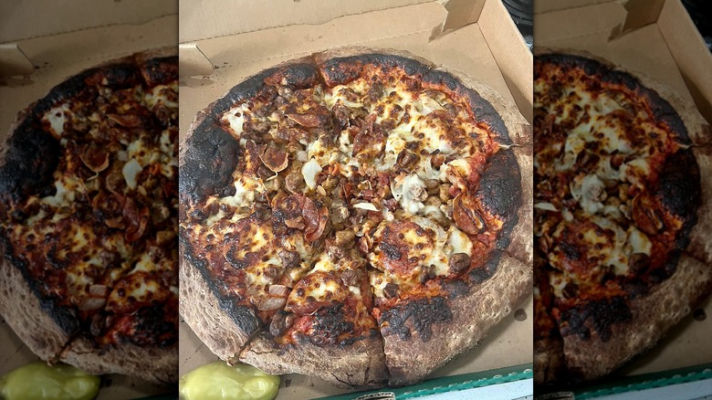 Burnt takeout chain pizza in box