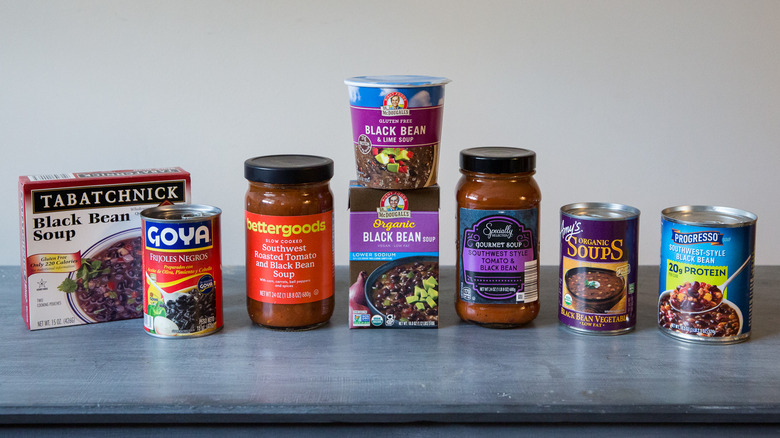 A black bean soup tasting bowl and package are sitting on a pink marble table.