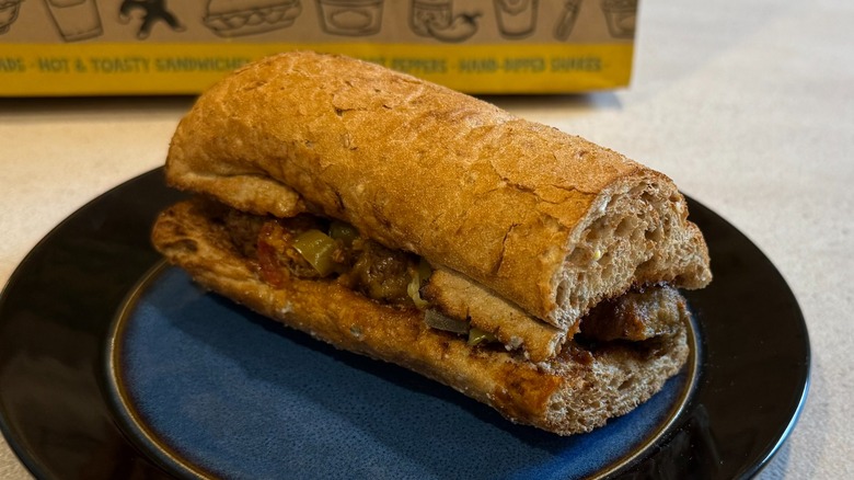 A sandwich with hot peppers on a black and blue plate