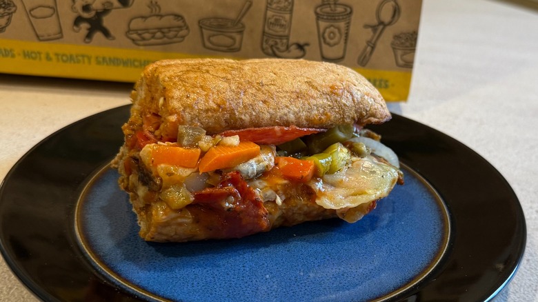 A sandwich with hot peppers and salami on a black and blue plate