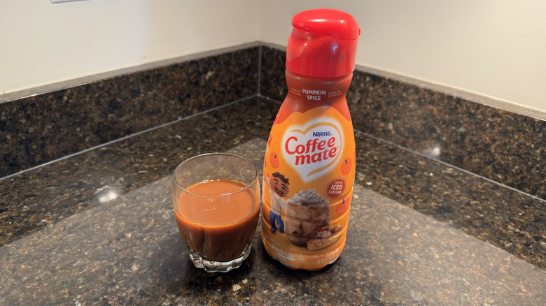 Coffee mate pumpkin spice creamer and glass of coffee on counter