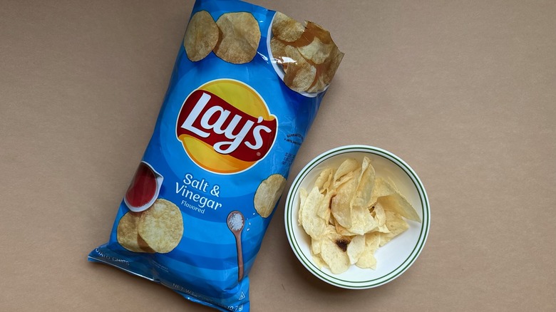 Bag and bowl of Lay's Salt & Vinegar Chips on brown surface