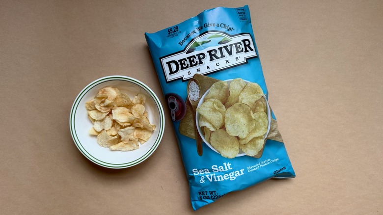Bag and bowl of Deep River Snacks Sea Salt & Vinegar Chips on brown surface