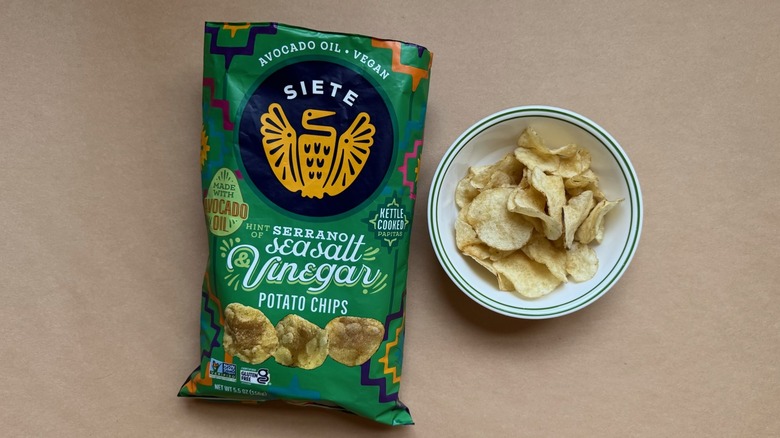 Bag and bowl of Siete Hint of Serrano Sea Salt & Vinegar Chips on brown surface