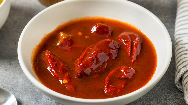 Chipotle peppers in adobo sauce in a white bowl.