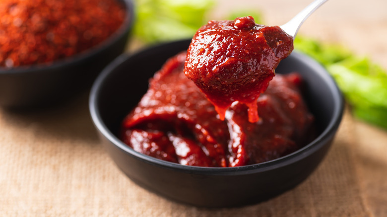 Bowl of gochujang with spoon lifting out a portion.