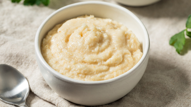 A bowl of prepared horseradish on cloth with a spoon.