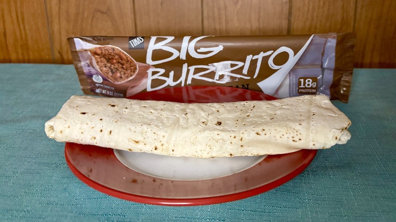 Tina's Big Burrito Beef & Bean on a red plate, in front of the burrito's packaging