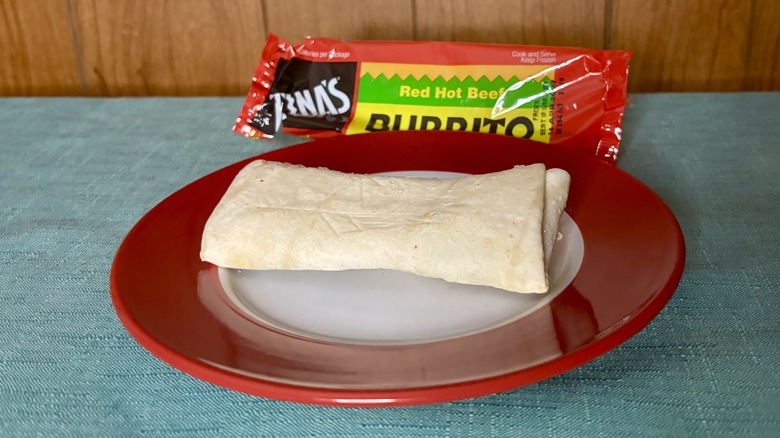 Tina's Red Hot Beef Burrito on a red plate, in front of the burrito's packaging