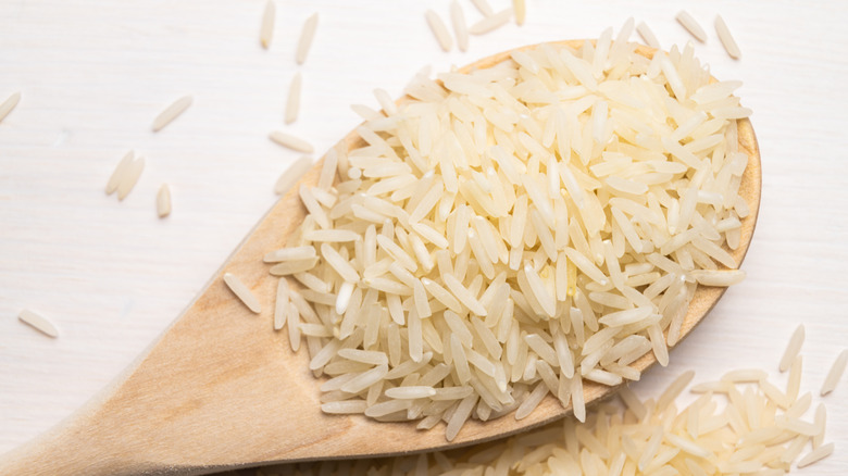 Close up of uncooked basmati rice uncooked in a wood spoon