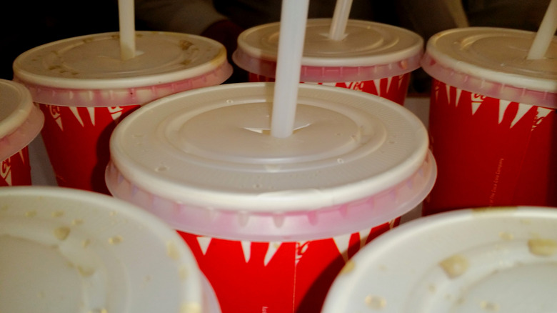 Several soda cups with lids and straws