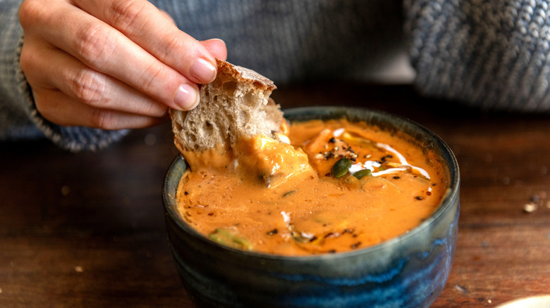 Bread is dipped into a bowl of soup