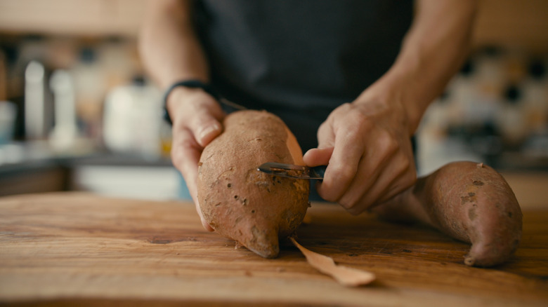 Sweet potatoes are peeled on a cutting board