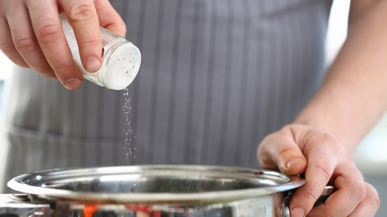 Salt is added to a pot of soup