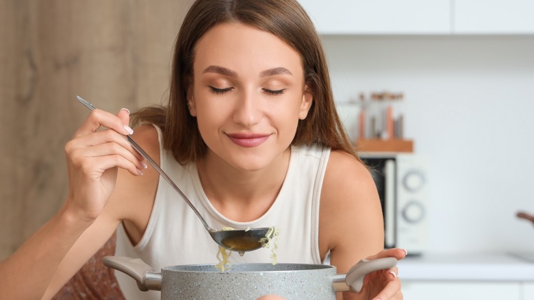 Woman tasting soup using a ladle from a pot