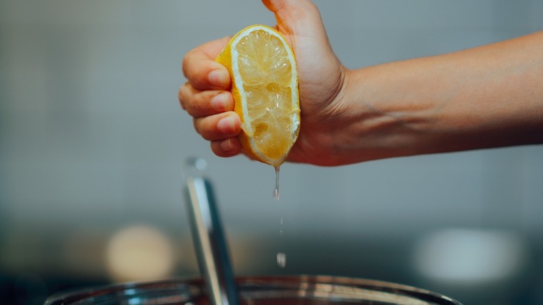 A hand squeezing a lemon into a pot