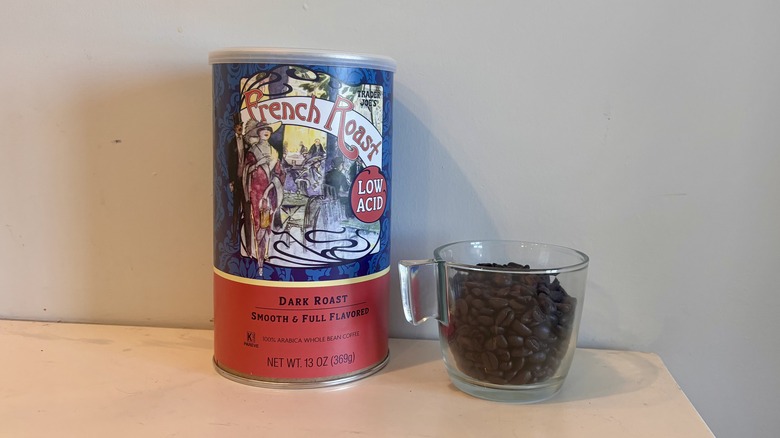canister of Trader Joe's coffee sitting next to a glass mug of coffee beans on a counter