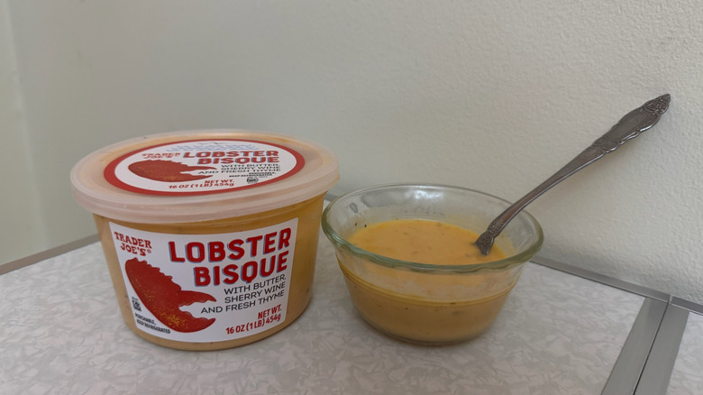 A tub and a small bowl of Trader Joe's Lobster Bisque with a spoon in it