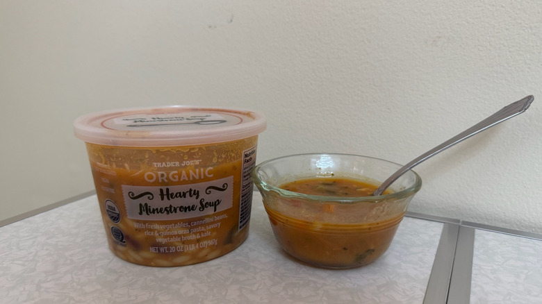A tub and a small bowl of Trader Joe's Organic Hearty Minestrone Soup with a spoon in it
