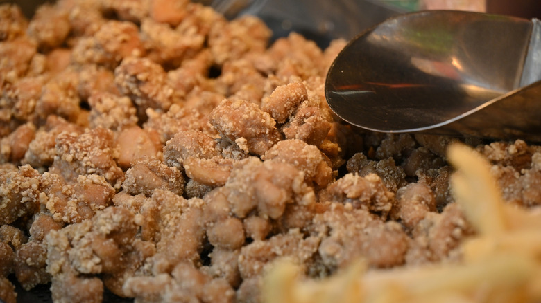 Closeup of yan su ji with a sauce-filled ladle above it