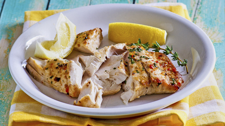 grilled fish fillets in white bowl with lemon