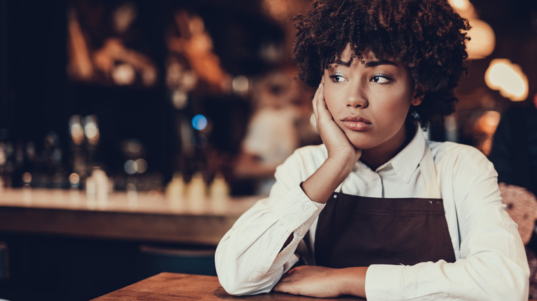 Upset-looking waitress stares off into distance