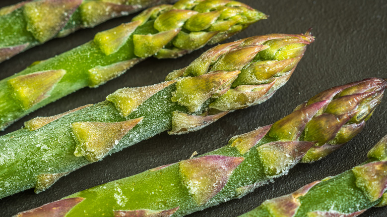 close up of frozen asparagus spears on a black background