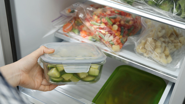 woman taking container of frozen zucchini out of the freezer