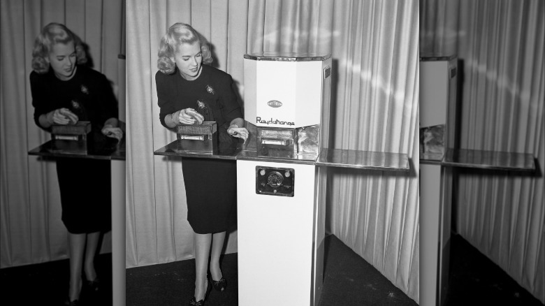 Black and white photo of a woman demonstrating how to cook a burger in an early Raytheon "Raydarange"