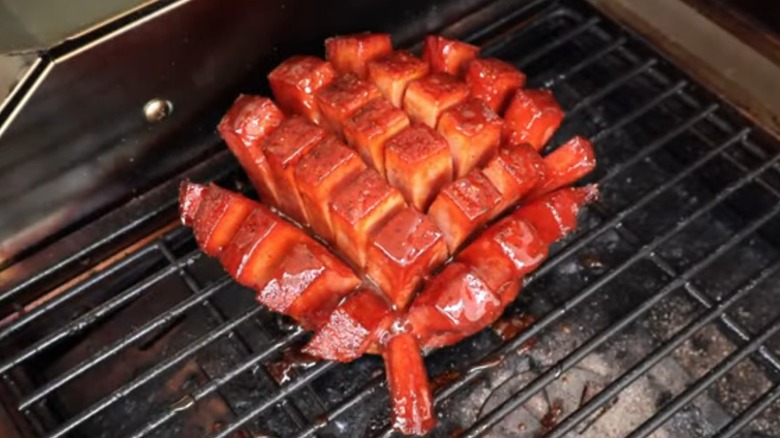 A bologna chunk that's been cross-cut and basted on a smoker grill