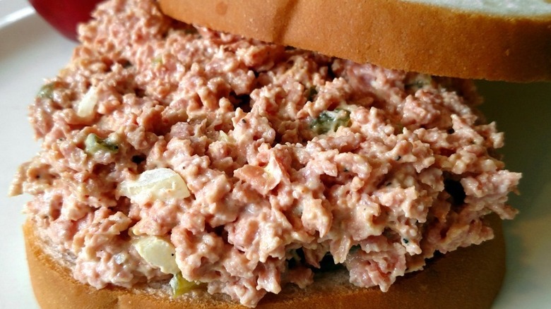 Finely ground bologna salad in a glass bowl on a wood table
