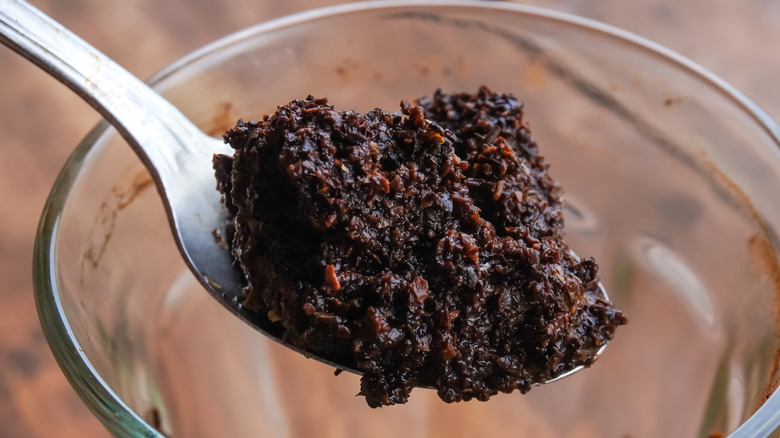 scooping a heaping spoonful of moist, used coffee grounds out of a glass