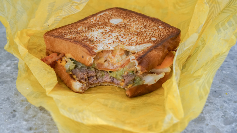 Close-up of Avocado Bacon Burger on yellow wrapper