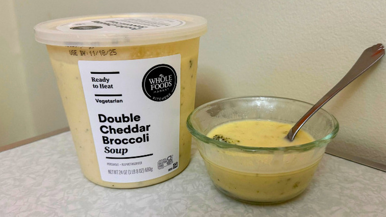 A tub and small glass bowl filled with Double Cheddar Broccoli Soup