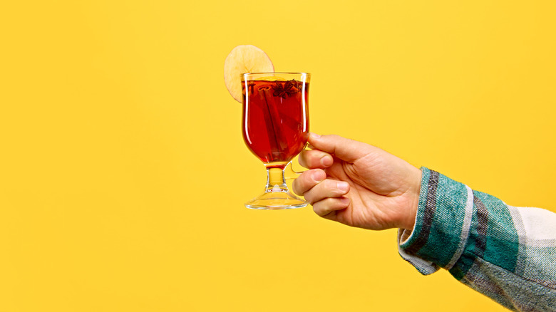 a woman holding a hot toddy on a yellow background
