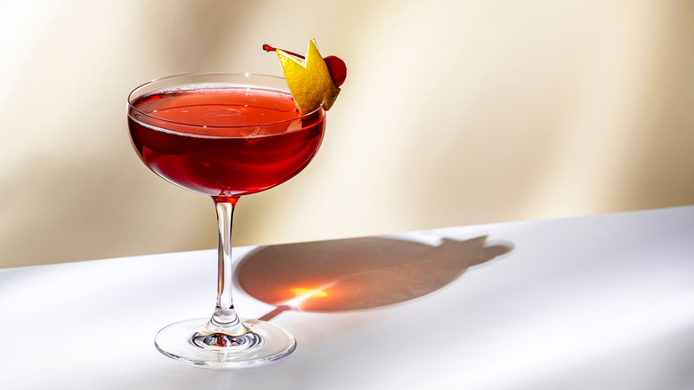 Manhattan cocktail with lemon peel and cherry on a white background
